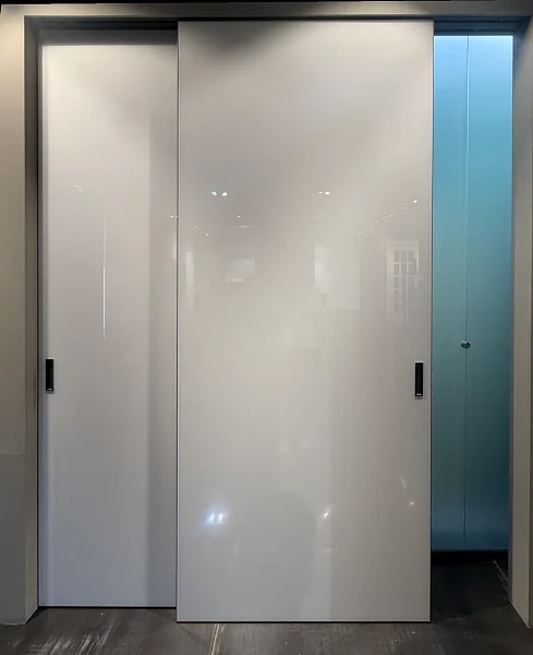 Раздвижная перегородка STRATUS-LAGO, модель Lira, крашеное глянцевое стекло в белом цвете, алюминиевый каркас полотна в чёрном цвете. Скрытый трек, крепление к верху проёма.