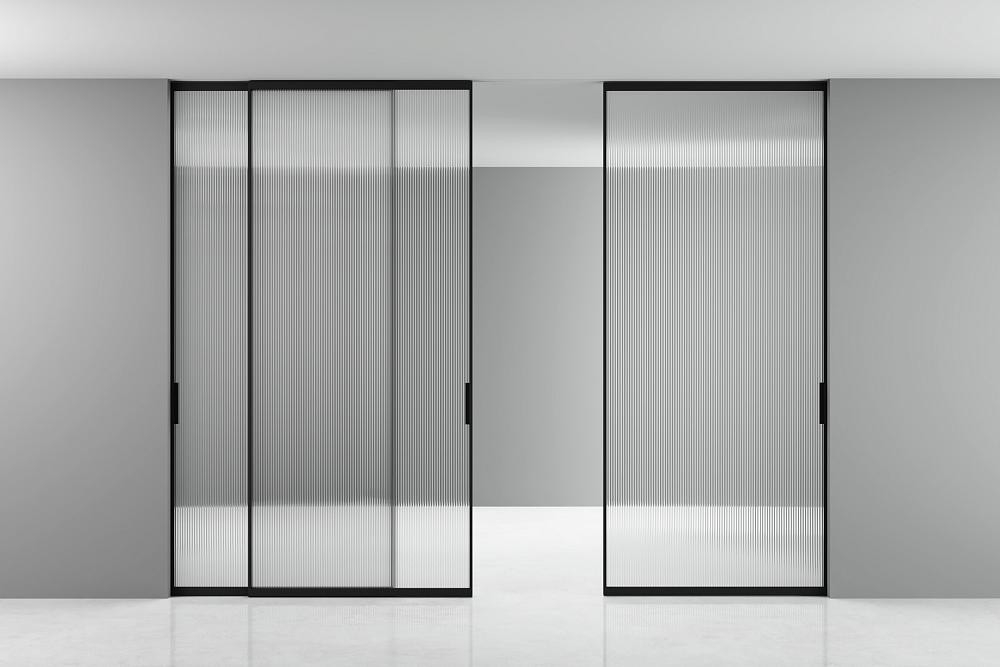 STRATUS-SLIM, модель Space, стекло прозрачное рифлёное GT05 Sole, алюминиевый каркас полотна в цвете AL08 Black. Раздвижная трехстворчатая перегородка в проёме, скрытый трек в потолке.